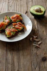 Homemade toast on brown dark wooden rustic background. Open sandwich with dark rye bread, avocado and salmon. top view, free space. Healthy protein food, breakfast, lunch concept. Gourmet snack