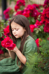 Cute girl in blossoming rose garden