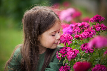Cute girl in blossoming garden with pink flowers