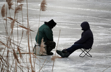 Fishermen on ice catch fish