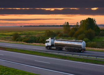 Isothermal Tank truck driving on highway. Oil and Gas Transportation and Logistics. Metal chrome...