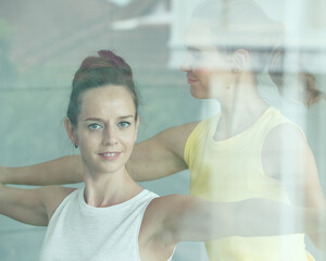Female yoga master teaching the student to start basic practice and helps her to arrange correct...