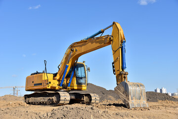 Fototapeta na wymiar Excavator on earthworks at construction site. Backhoe on foundation work and road construction. Heavy machinery and construction equipment