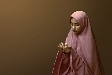 Fototapeta na wymiar Asian Muslim woman in a veil standing while raised hands and praying