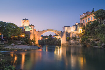 Night cityscape view of the iconic illuminated Stari Most bridge, Neretva River and old town of Mostar, Bosnia and Herzegovina.
