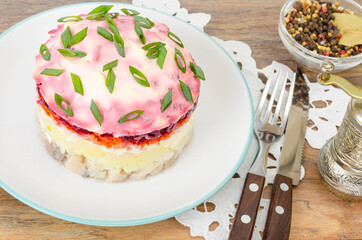 Plate with appetizer of beets, carrots, potatoes and salted fish on wooden table