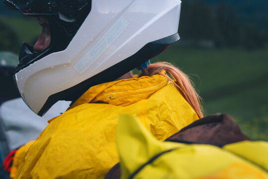 A girl in a yellow raincoat and a motorbike helmet. Motorcyclism and travel. close-up. Top of the Mountains. A day with clouds. Difficult test and extreme vacation. Biker outfit.