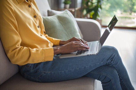 Cropped photo portrait of african american woman sitting on couch working on laptop typing in modern office indoors