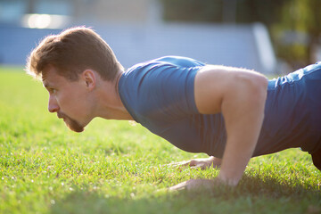 Enduring concentrated man doing push ups