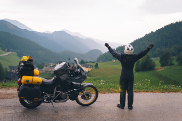 A motorcycle driver stands with arms outstretched on the sides, Adventure vacation, biker dressed...