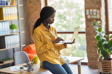 Profile side photo of concentrated afro american business woman sit on table browse internet laptop...