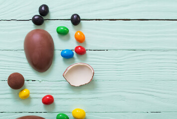 Easter chocolate eggs and candies on green wooden background