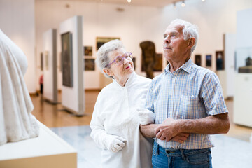 Obraz premium mature European couple examines paintings in an exhibition in hall of art museum
