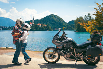 Happy biker couple in love travel together. Stands by a motorcycle with bags. Tourism and vacation....