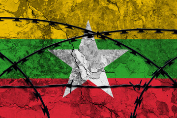 The national flag of Myanmar (Burma) painted on a grungy wall with Barbed wire in the foreground....