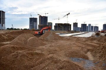 Excavator doing earthworks during the construction of a road in a new residential area in the city....