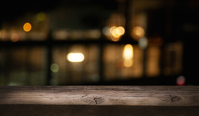 empty wooden table on blurred light gold bokeh of window cafe restaurant on dark background, place for your products on the table