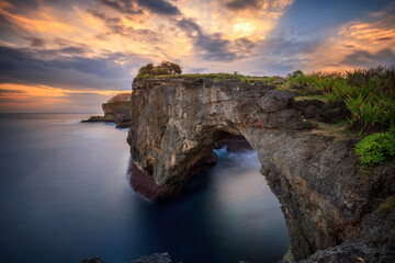 Fototapeta na wymiar Stone arch over the sea. Broken Beach, Nusa Penida Island , Bali, Indonesia in sunset time