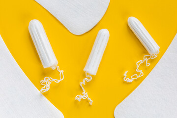 Feminine hygiene protection. Natural cotton tampons and pads on a yellow background..Menstrual period concept.