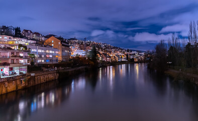 Fototapeta na wymiar Blue hour in Zürich, the largest city in Switzerland. Illuminated houses along the Limmat River and their reflections in the water