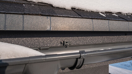 The corner of the roof with a drainage system, on the roof lies snow