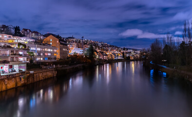 Fototapeta na wymiar Blue hour in Zürich, the largest city in Switzerland. Illuminated houses along the Limmat River and their reflections in the water