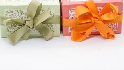 Pink gift box near the green box with bows for a celebration