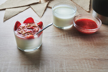 natural yogurt dessert decorated with strawberries and dried fruits on a wooden table