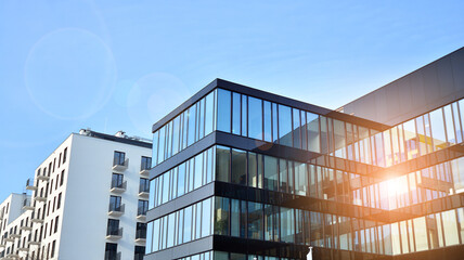 Obraz premium A residential building and an adjacent office building. Modern urban development. Buildings against blue sky and sun light.