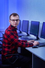 Vertical photo of a man with glasses for vision. Prescribes the code on the computer. The work of a programmer in the office.