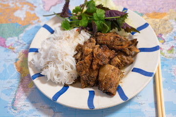 Vietnamese meal "bun cha" (grilled loaded pork fatback) with rice noodle and fresh herb on plate.