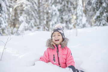 Fototapeta na wymiar Cute girl playing outdoor in winter fresh white snow sitting on ground.