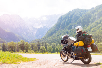 Girl in full body protection. Hermetic packing bag. Water resistant, tourer motorcycle for traveling with large luggage, on a background of green mountains, travel and freedom