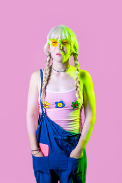Studio shot hippy playful caucasian woman blowing, popping and chewing bubble gum