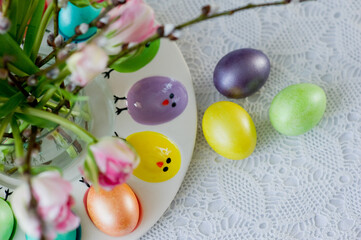 Fototapeta na wymiar Easter still life with a bouquet of tulips and willow, Easter eggs and cake in pastel colors