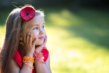 Portrait of pretty fashionable child girl in red dress enjoying warm sunny summer day.