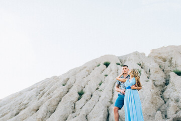 blonde girl in a light blue dress and a guy in a light shirt in a granite quarry
