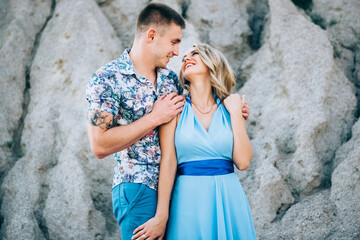 blonde girl in a light blue dress and a guy in a light shirt in a granite quarry