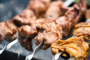 Shashlik or shish kebab preparing on barbecue grill over hot charcoal. Grilled pieces of pork meat on metal skewers.