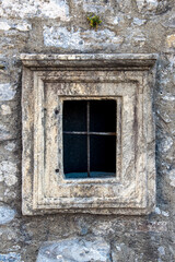 Fototapeta na wymiar old stoned window with iron bars in an old wall