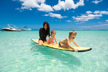Twins, boy and girl with mom surfing in the ocean on a blackboard