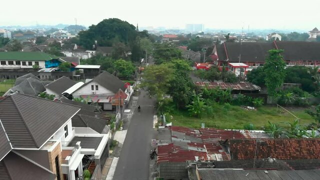 The quiet traffic in small road aerial footage cityscape view Yogyakarta city from drone flying over to the trees and reveal shot of neighbourhood