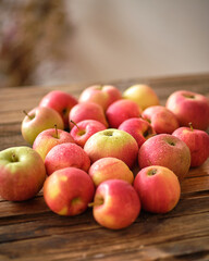 Lots of red apples are lying on a wooden table in the bright sunlight