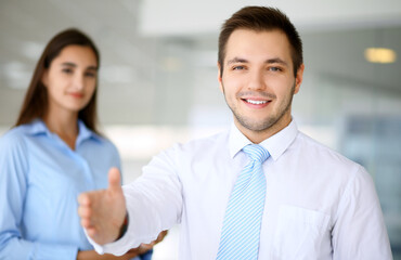 Smiling businessman in office with colleagues in the background