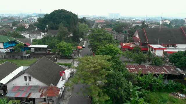 Aerial footage neighbourhood with houses and green trees in Yogyakarta city from drone flying above