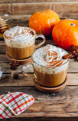 Pumpkin spiced latte or coffee in a glass on a vintage table. Autumn or winter hot drink.
