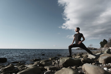 Attractive young man practicing yoga meditation and breathwork outdoors by the sea