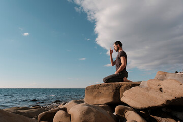 Attractive young man practicing yoga meditation and breathwork outdoors by the sea