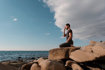 Attractive young man practicing yoga meditation and breathwork outdoors by the sea