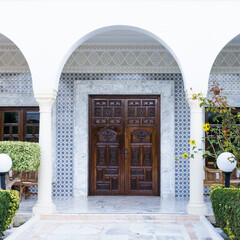 The arcade and the wooden door in the oriental style are decorated with ceramic mosaics - 412168012